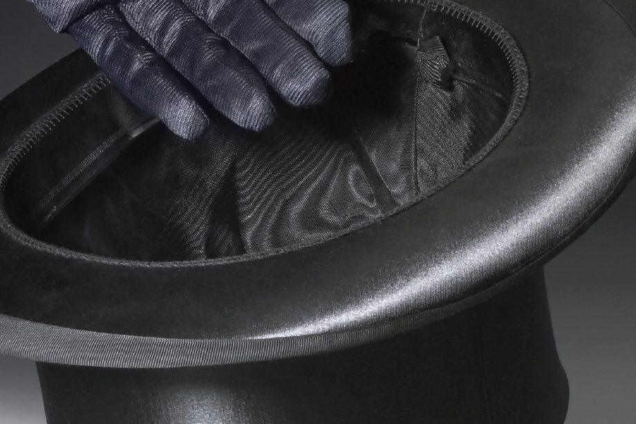 A black top hat with a gloved hand reaching inside.