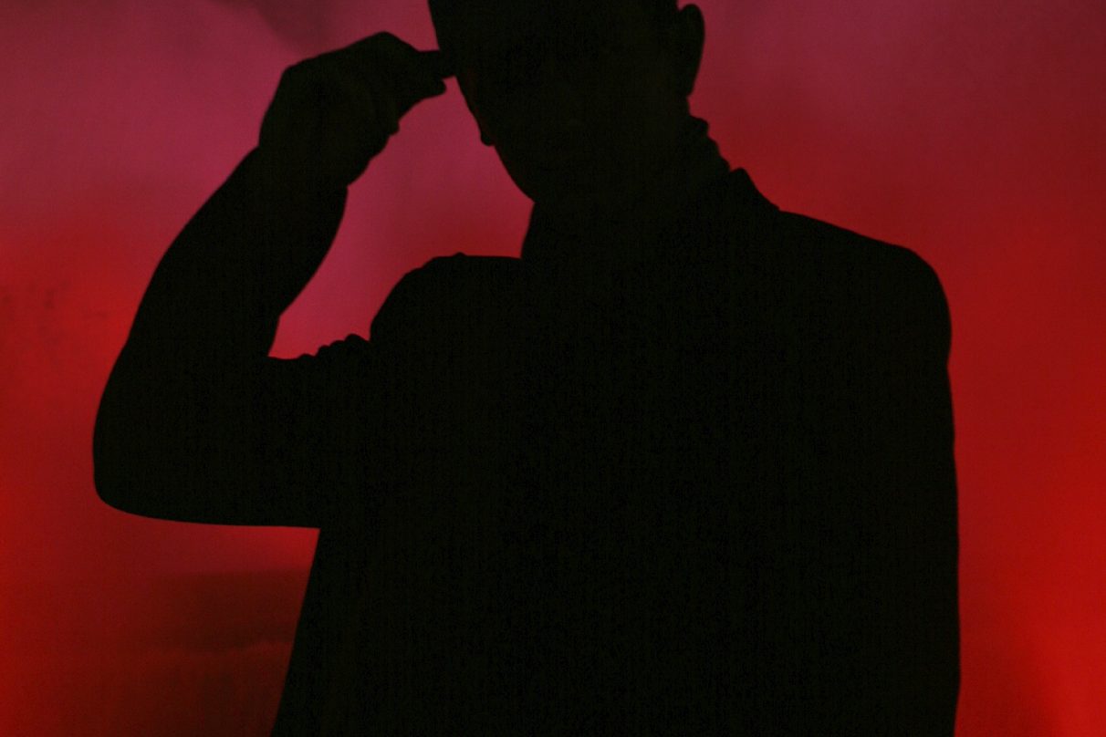 Silhouette of a person against a red and smoky background.